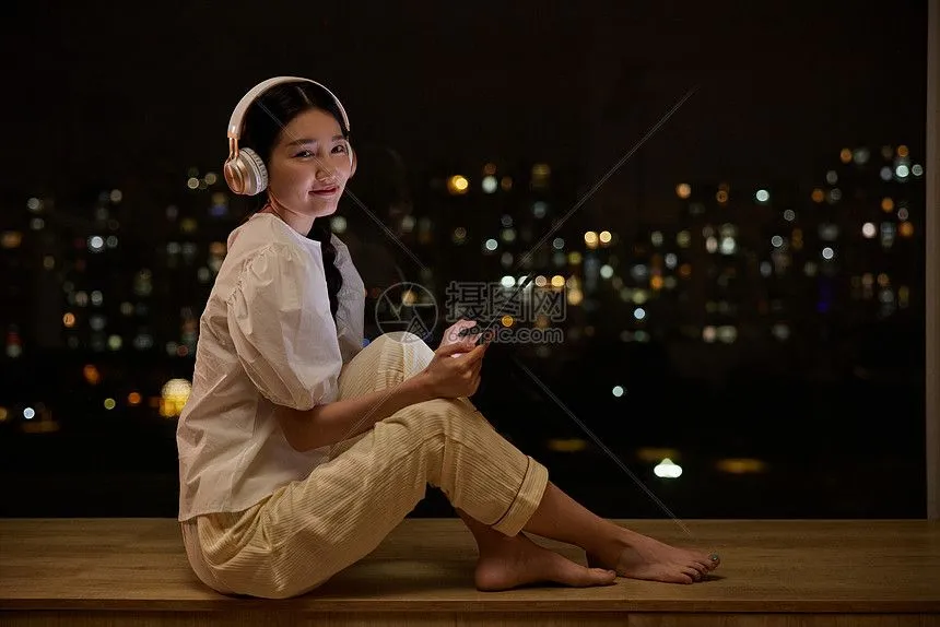 一个人在夜晚窗边安静听歌的剪影